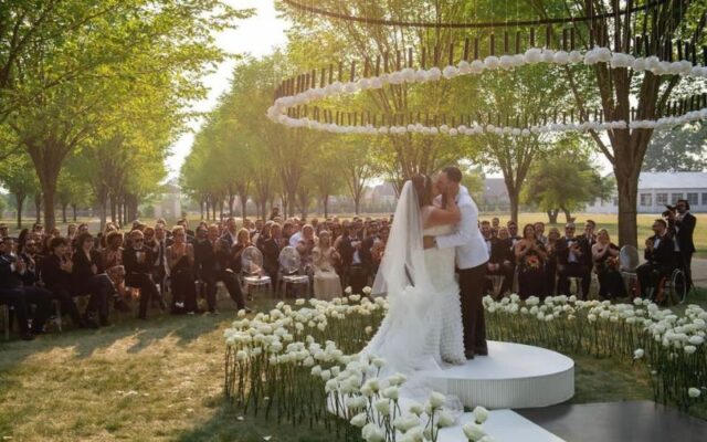 Alaina and Matt dancing at their reception surrounded by white floral décor and evening light.